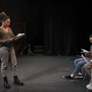 Pessoas ensaiando em palco de teatro.