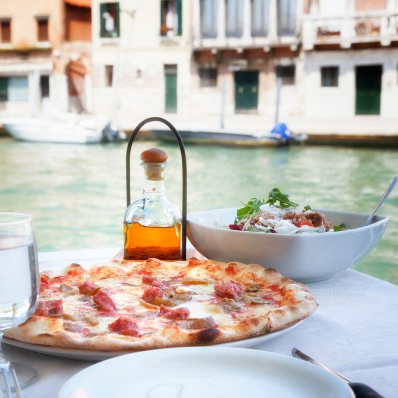 Pizza italiana com vinho servidos em mesa ao ar livre em Veneza.