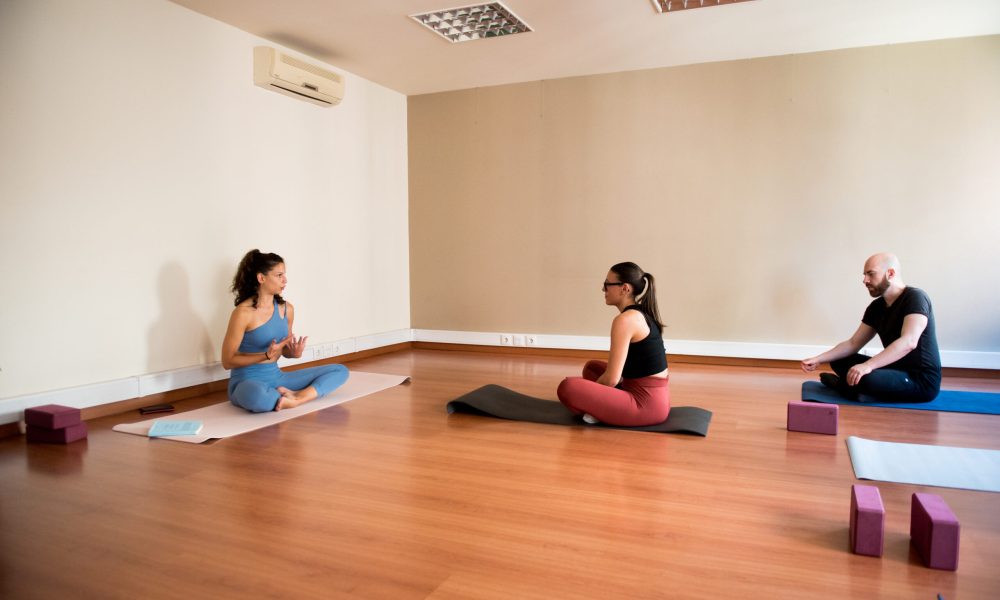 Aula de yoga em estúdio com espelhos.