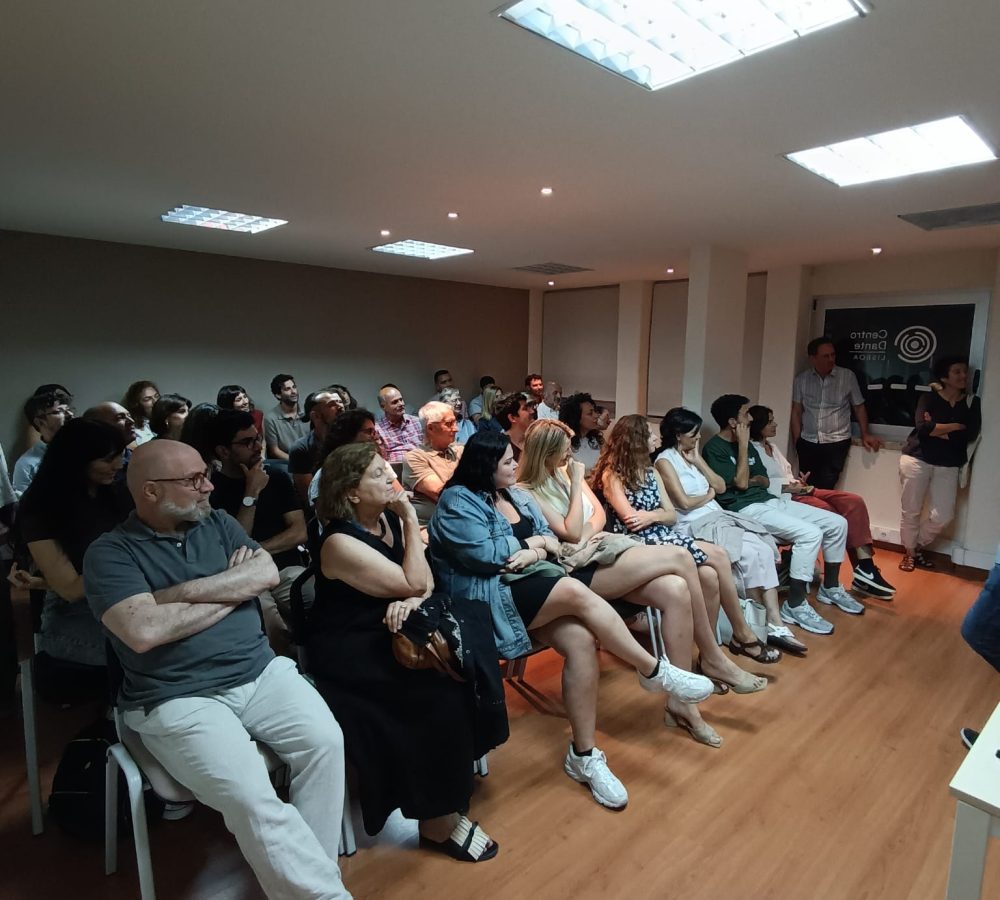 Sala de aula, com pessoas sentadas a assistir um filme