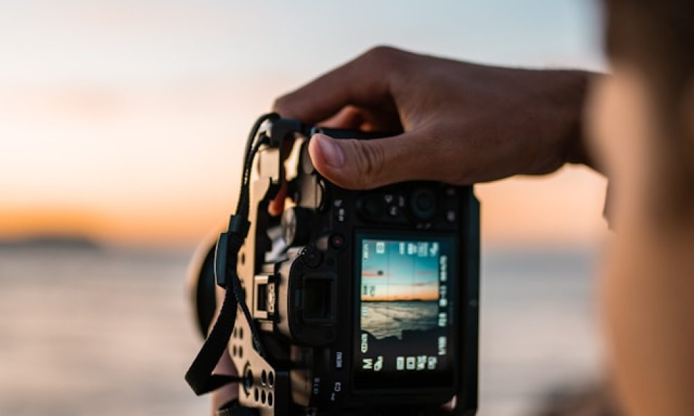 homem tirando foto de uma paisagem com por do sol