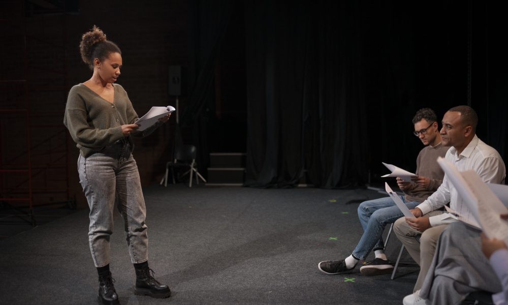 Pessoas ensaiando em palco de teatro.